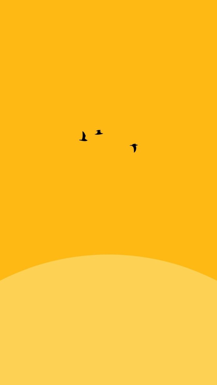 Silhouetted birds flying against a yellow sky at sunset