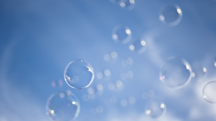 Transparent bubbles floating against a blue sky background