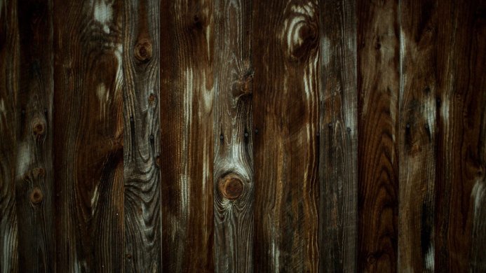 Close-up of a dark brown wooden plank surface with knots and nail heads