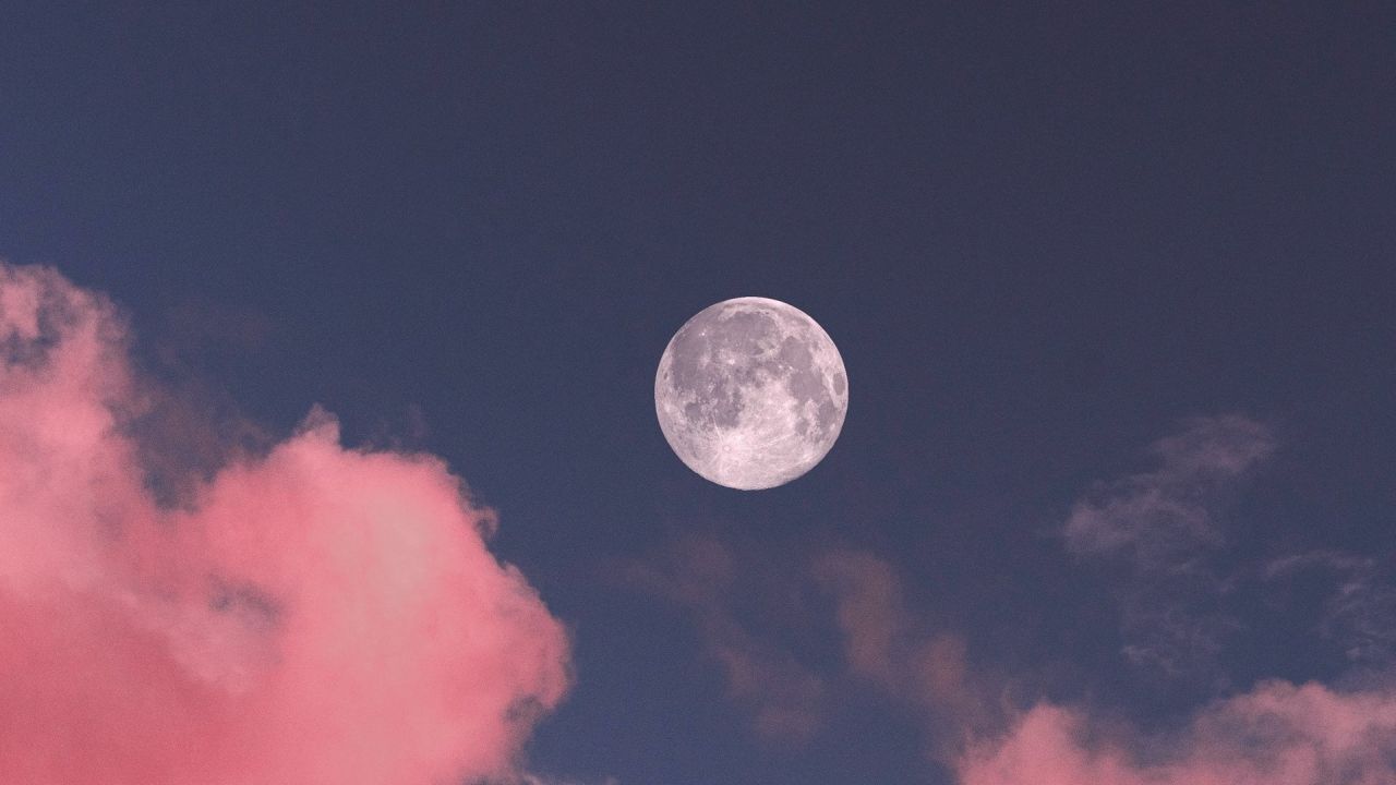 Full moon and pink clouds in dark sky
