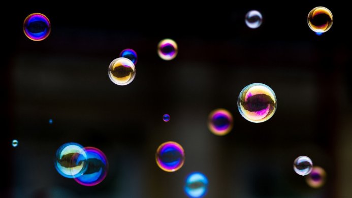 Floating iridescent soap bubbles against a dark background
