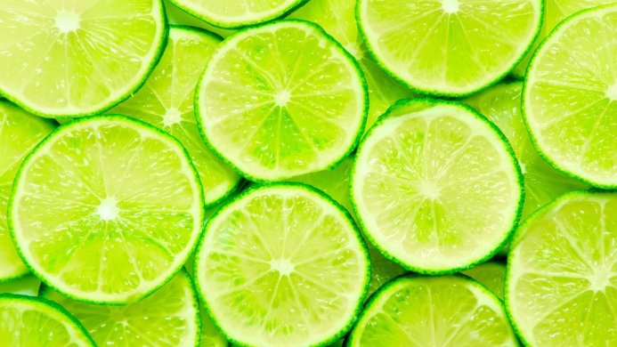 A pile of vibrant green lime slices creating a refreshing and juicy background
