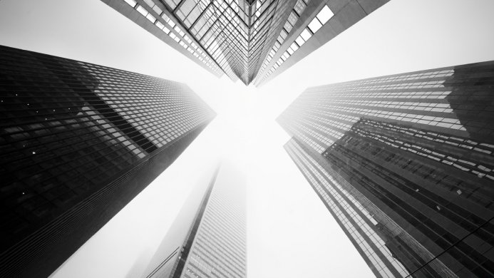 A low angle shot of skyscrapers disappearing into the fog in black and white
