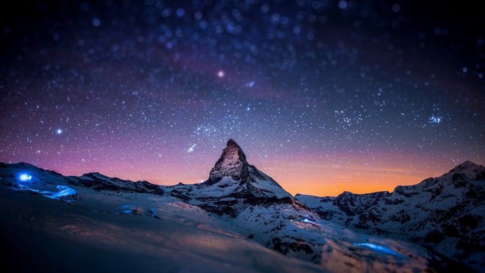 Matterhorn mountain under a starry night sky, with snow-covered peaks