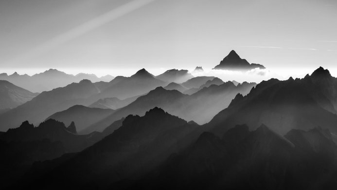 Black and white image of mountain peaks shrouded in mist