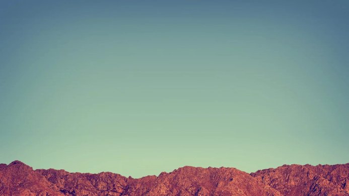 Brown mountain range against a light blue sky