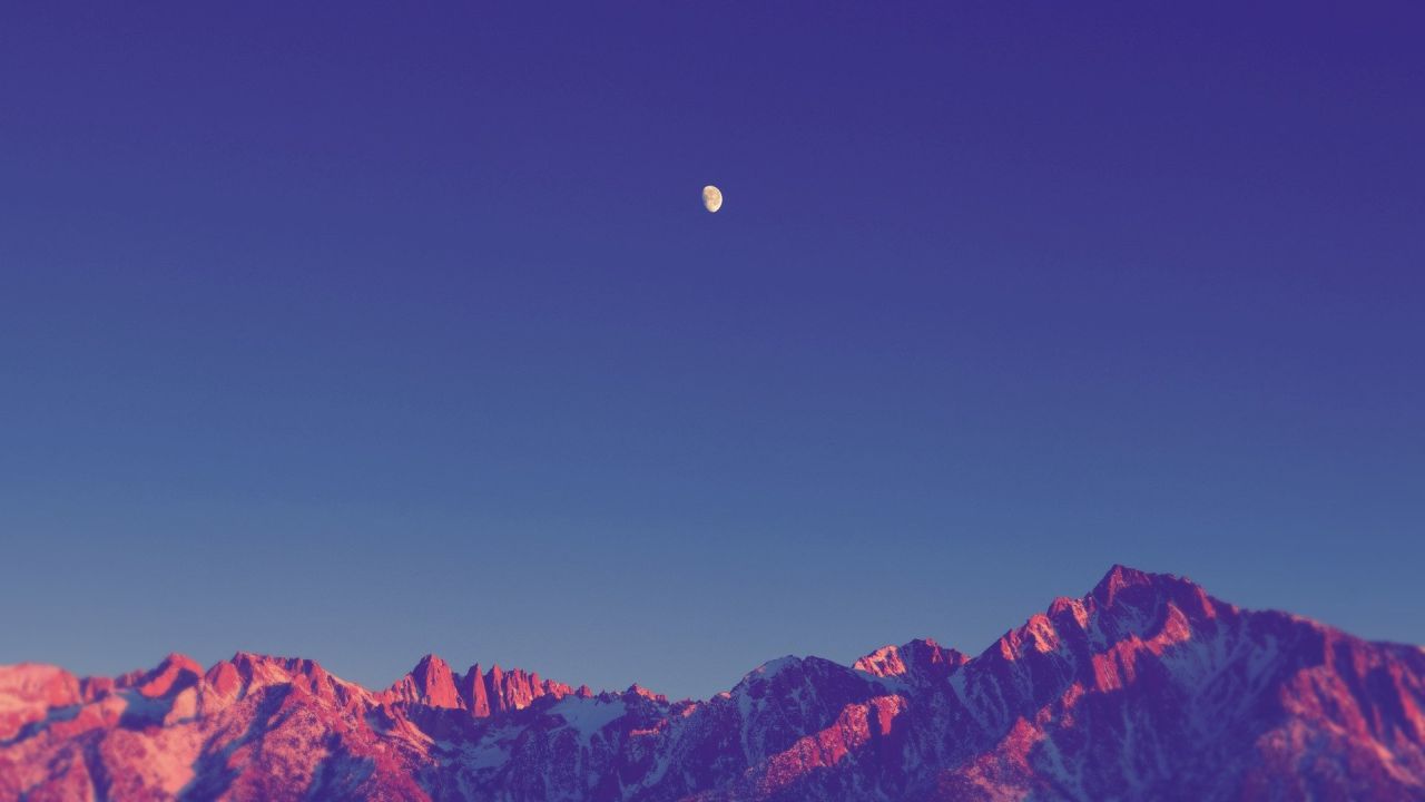 Mountain peaks with golden light under a moonlit sky