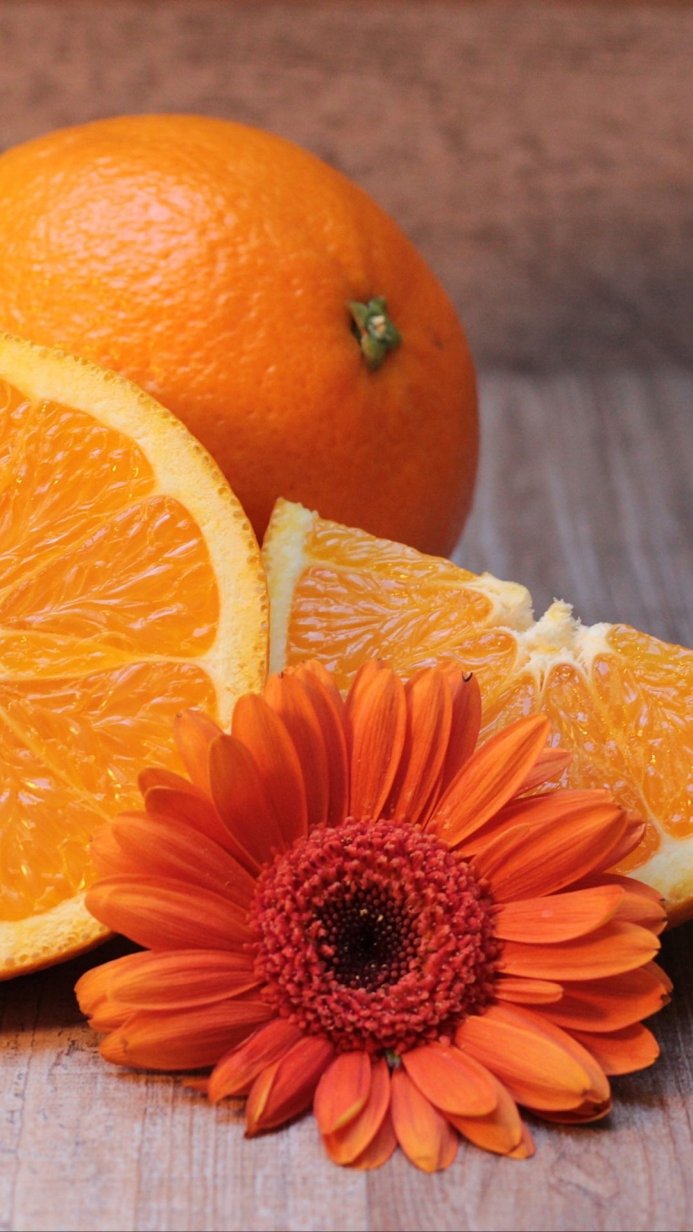 Close-up of oranges and a gerbera flower on a wooden surface