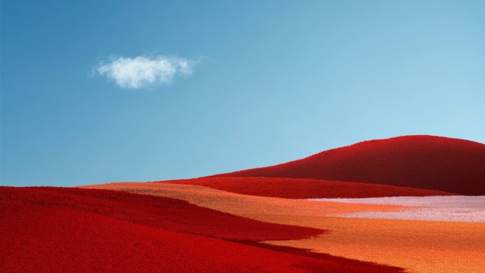 Rolling red and orange hills under a blue sky with a single cloud