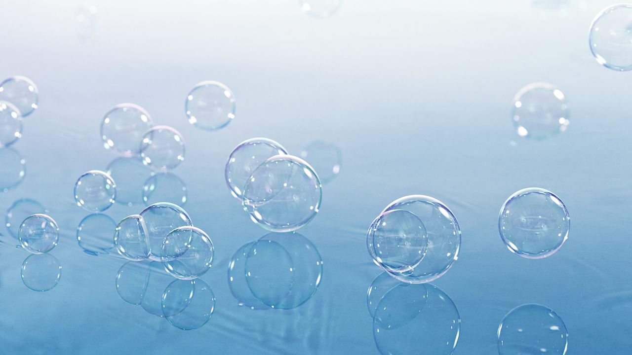 Transparent soap bubbles on reflective blue surface