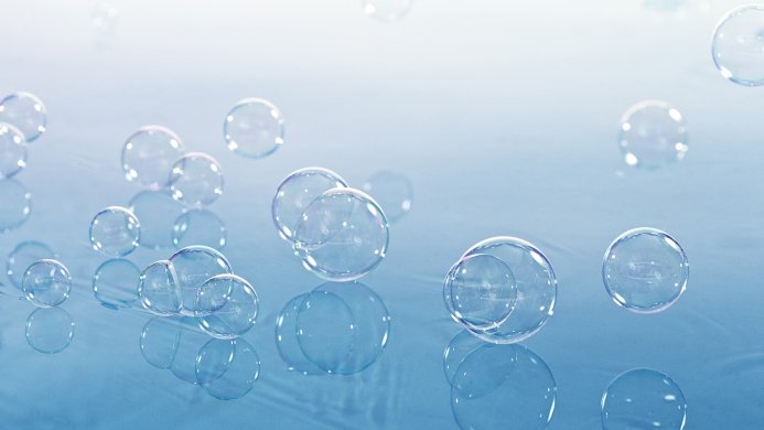 A group of transparent bubbles on a light blue reflective surface