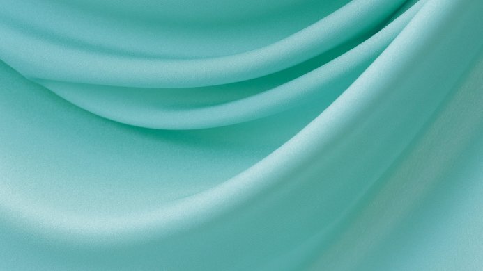 A close-up of turquoise fabric with soft folds