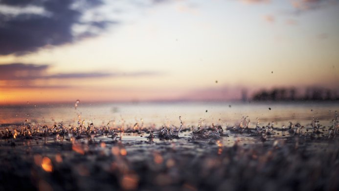 Water drops on a water surface with a sunset on the background