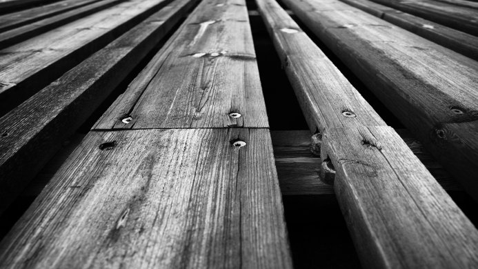 Black and white image of weathered wooden planks with visible wood grain and nails
