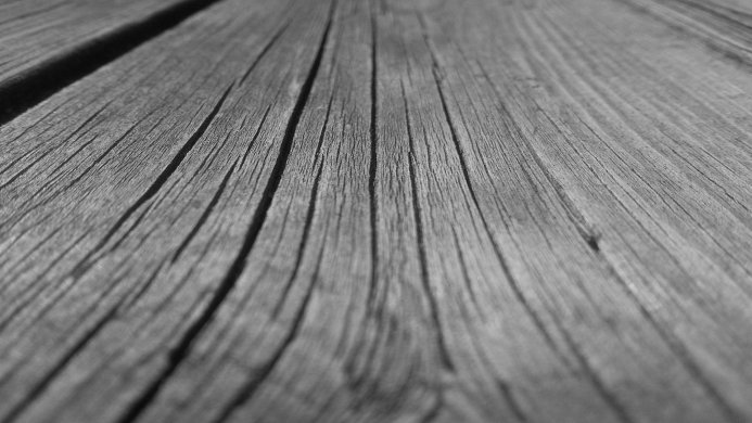 Close-up of weathered wooden planks showing detailed wood grain in monochrome
