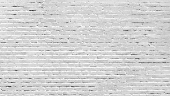 A white painted brick wall with a rough texture, showcasing a repeating pattern