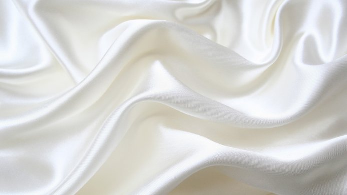Close-up of draped white silk fabric, showcasing its smooth texture and subtle folds