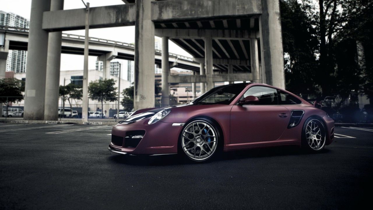 Maroon Porsche 911 under bridge