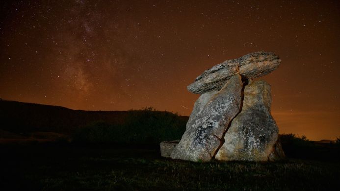 Dolmen stone structure at night under a starry sky with the Milky Way visible