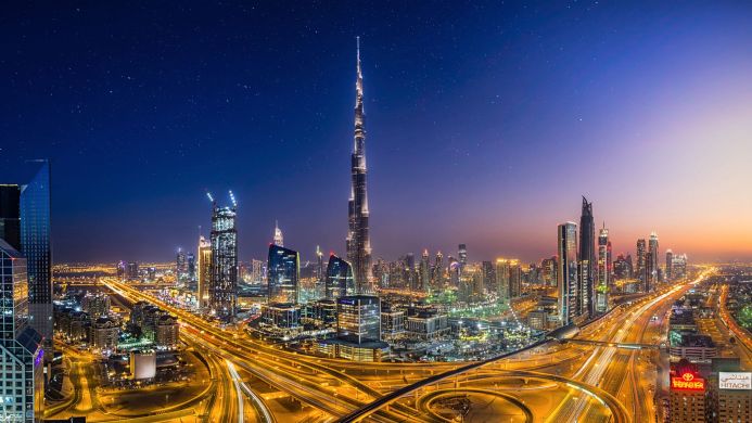 Dubai skyline with Burj Khalifa at night, illuminated skyscrapers and highway lights