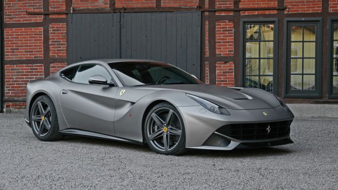 Gray Ferrari F12berlinetta parked in front of a brick building