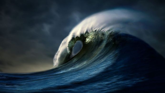 A large, powerful wave cresting in the ocean with dark clouds in the background