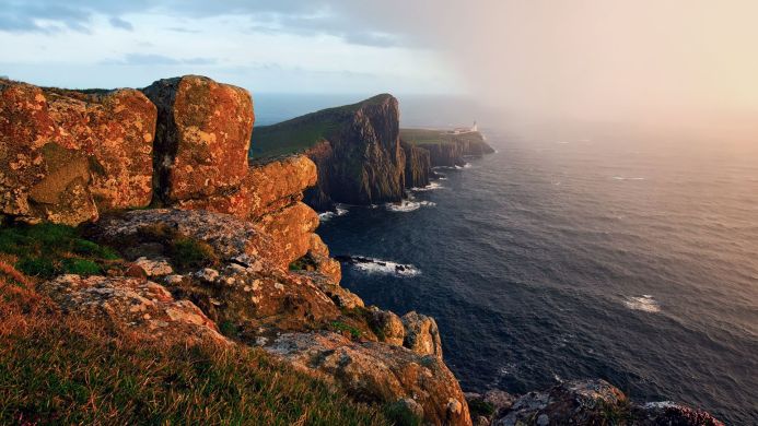 Coastal view of a lighthouse on a cliff with the ocean in the background