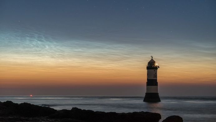 A lighthouse at dusk with noctilucent clouds in the sky