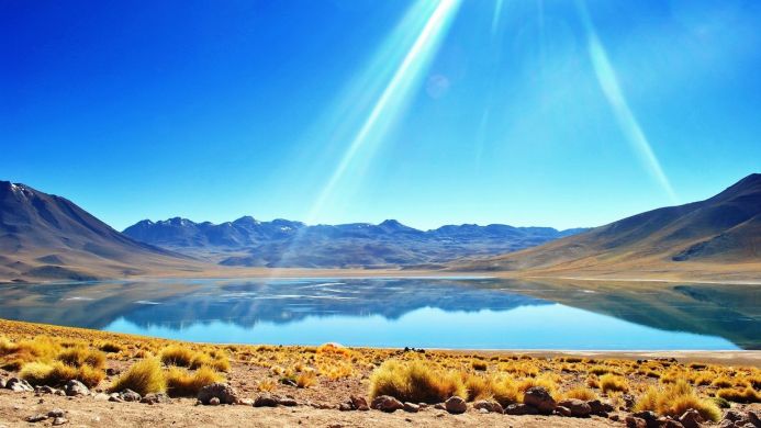 Scenic view of a lake reflecting mountains under a clear blue sky