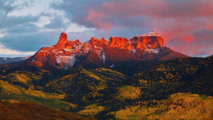 Mountain range during golden hour with autumn trees and a red sky