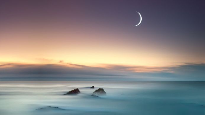 Ocean with rocks, moon and sunset. Very long exposure