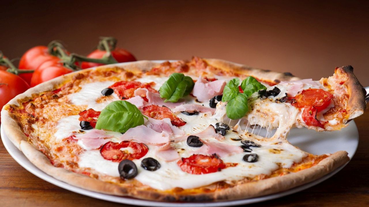 Pizza with ham tomatoes and basil