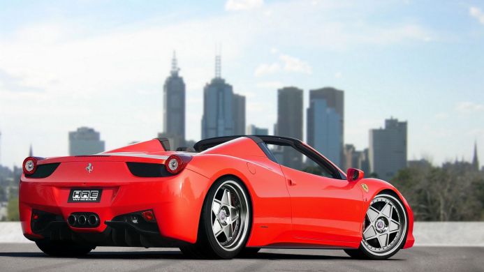 Red Ferrari 458 Spider with custom HRE wheels against a city skyline