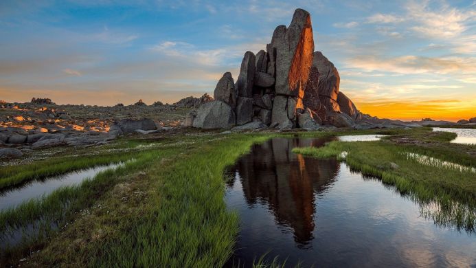 A rocky landscape with a stream and reflections at sunset
