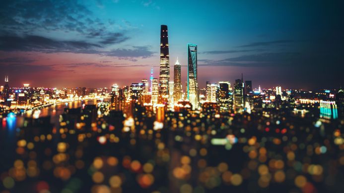Shanghai cityscape at night with illuminated skyscrapers and blurred lights in the foreground