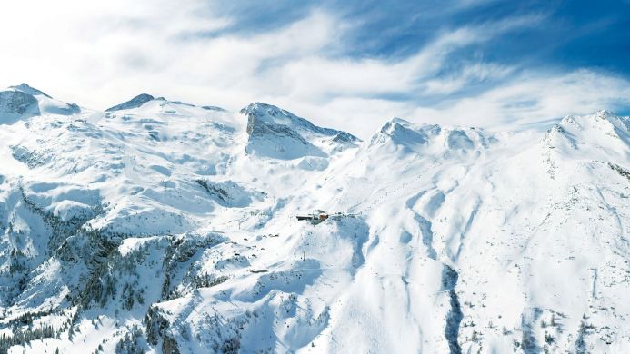 Snowy mountain range under a blue sky with clouds