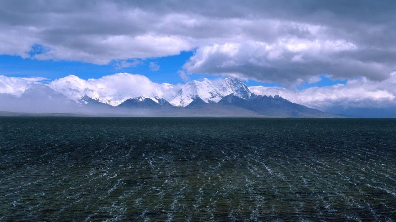 Snowy mountains over a dark lake
