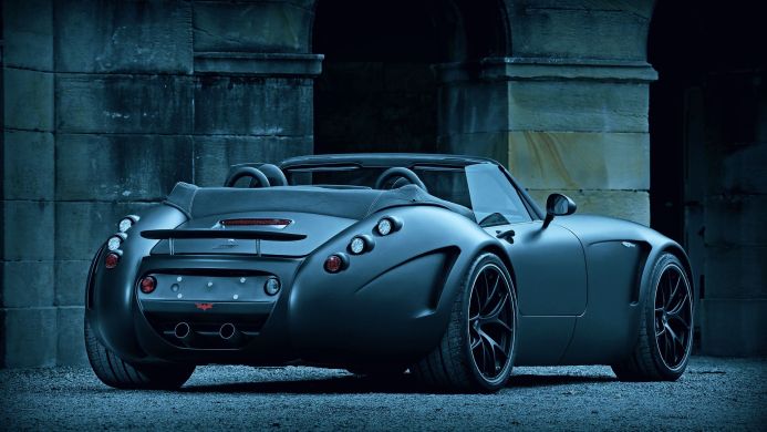 A gray Wiesmann Roadster MF5 parked in front of a stone building