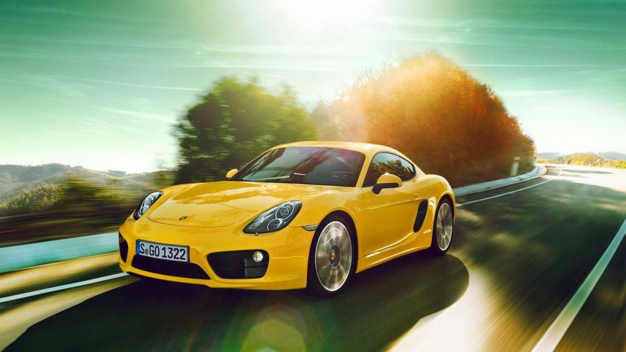 Yellow Porsche Cayman driving on the road