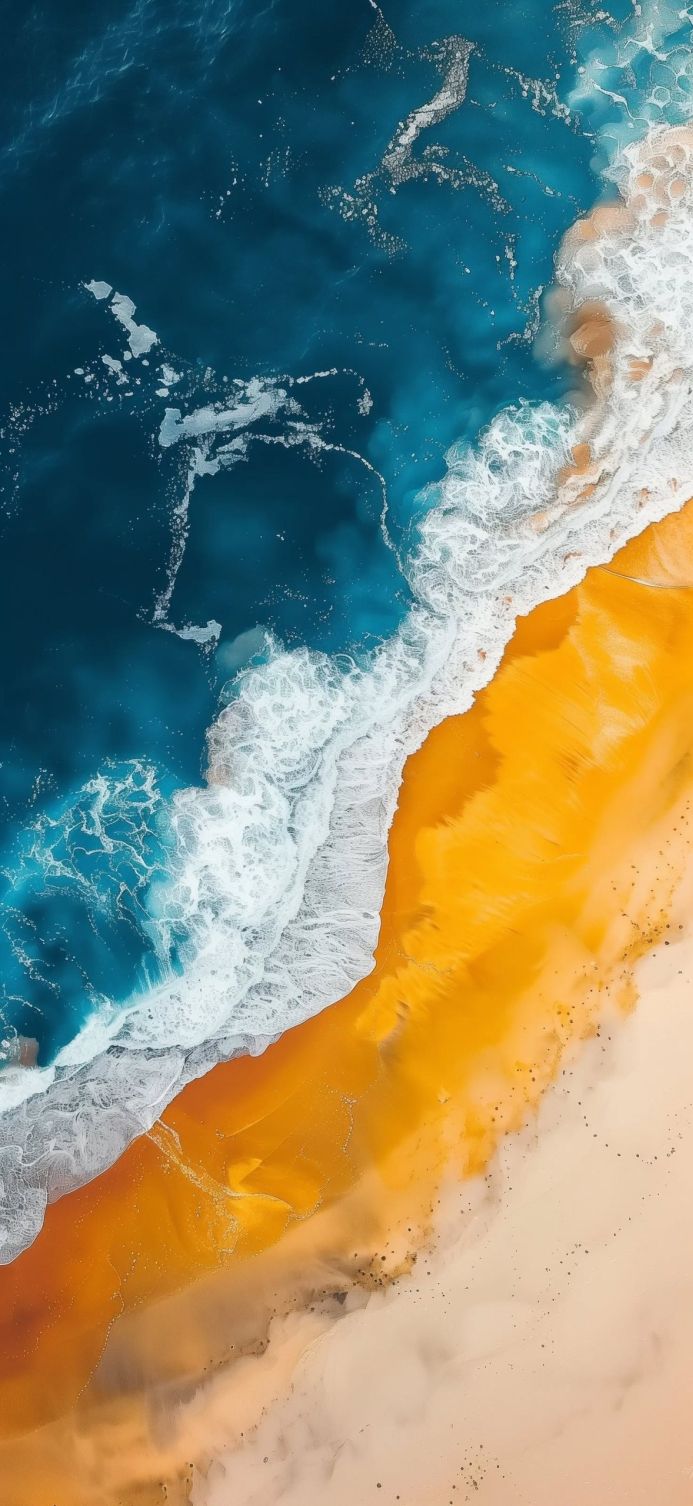 Aerial view of a beach with yellow sand and blue sea with white waves