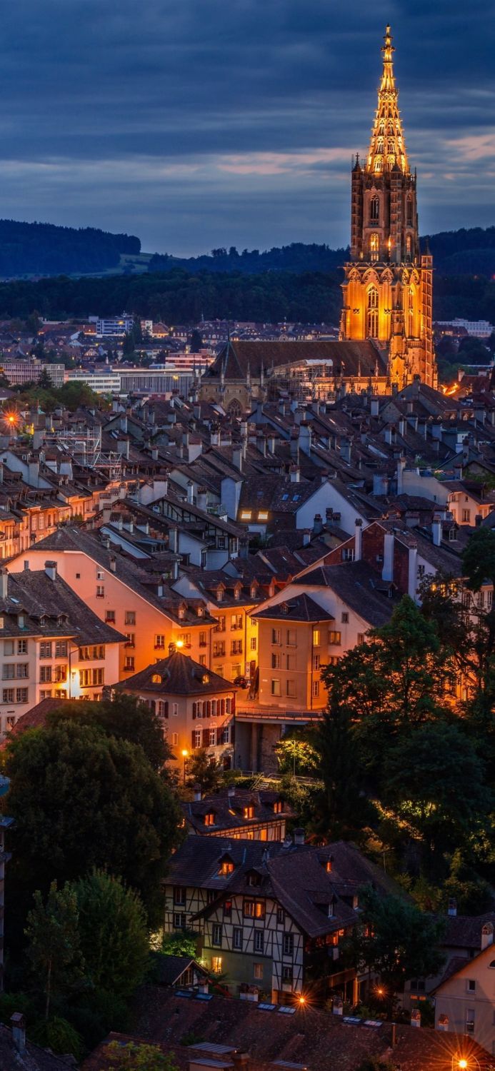 Bern Minster in Bern, Switzerland at dusk. A detailed cityscape with warm lights