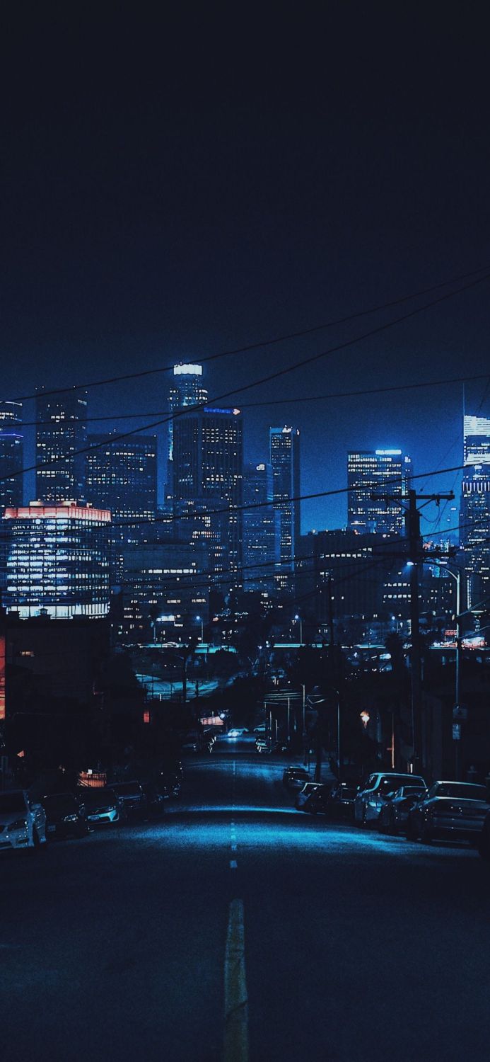 Cityscape at night with illuminated buildings and a road leading to the city