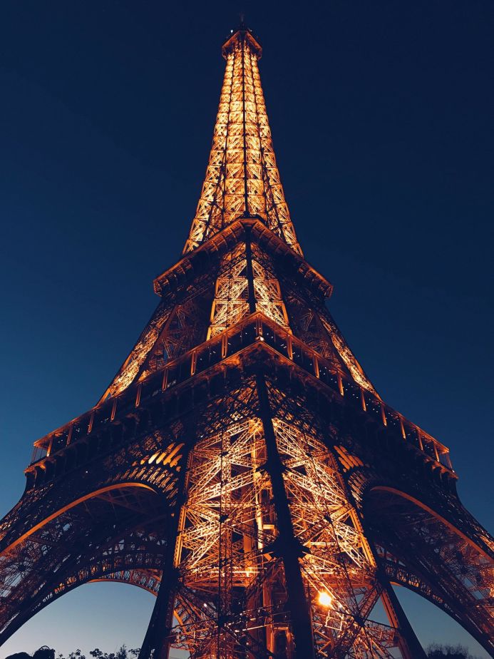 The Eiffel Tower illuminated at night against a dark blue sky in Paris, France