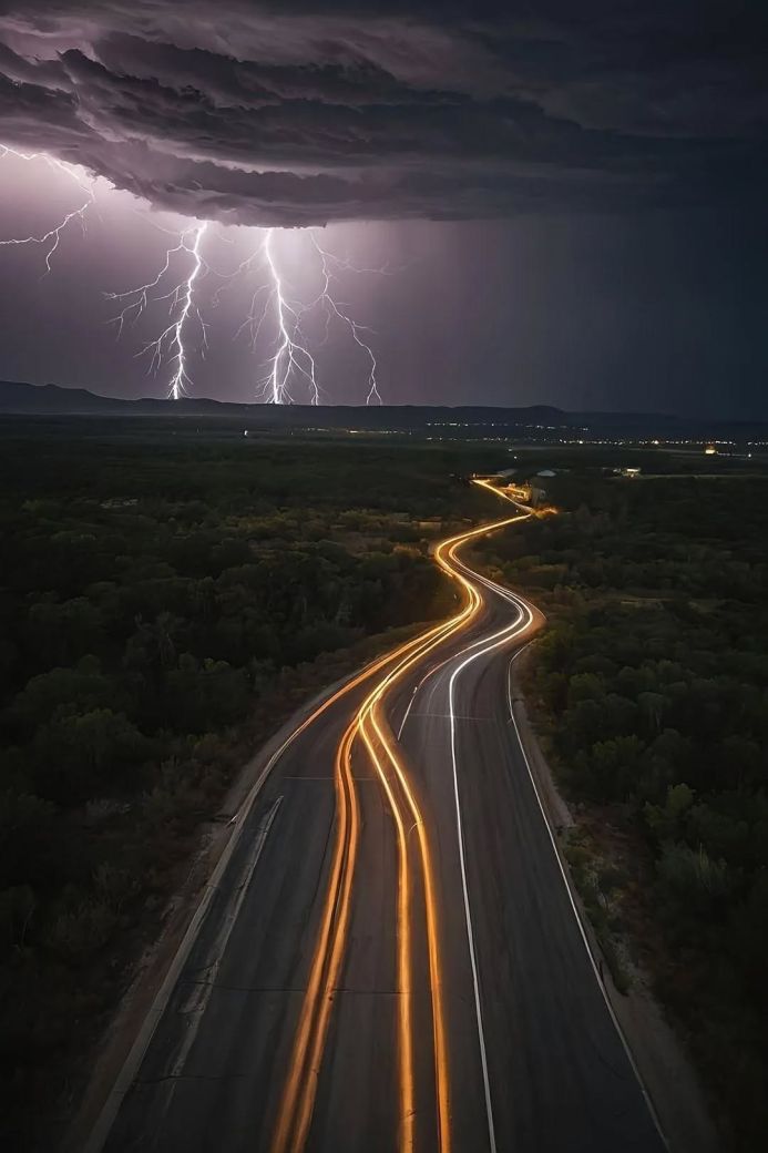Lightning strikes over a winding road at night, captured with long exposure