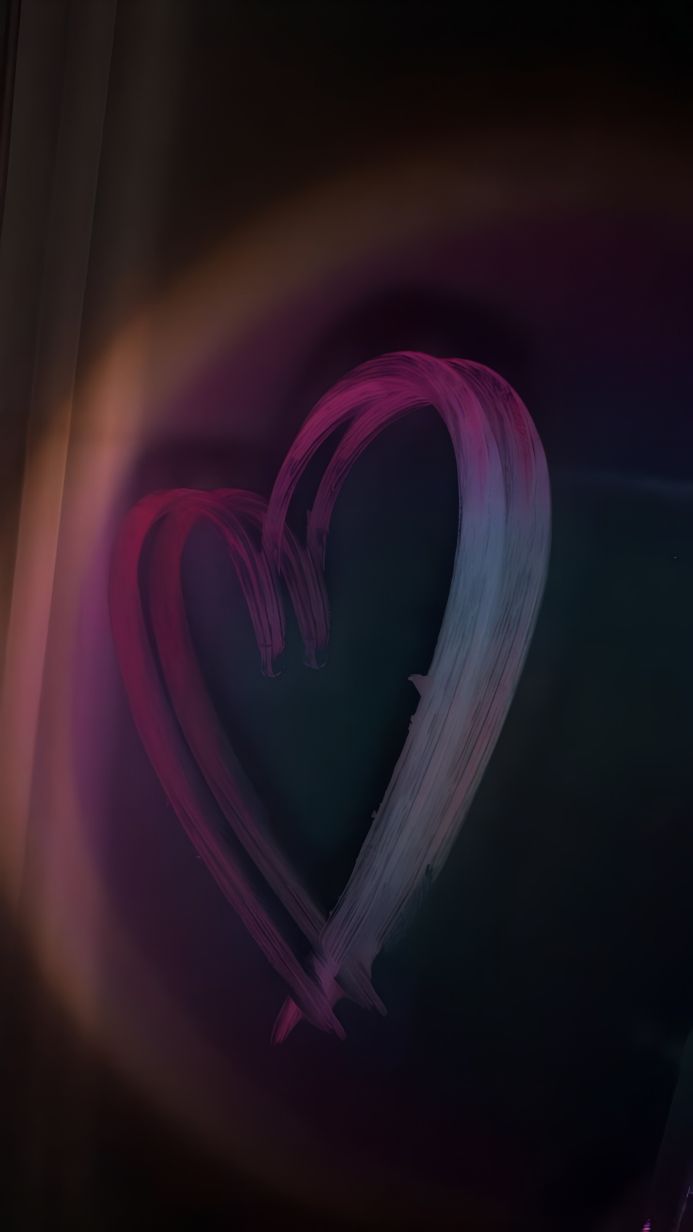 A heart shape painted with brush strokes on a dark surface with a soft, luminous glow