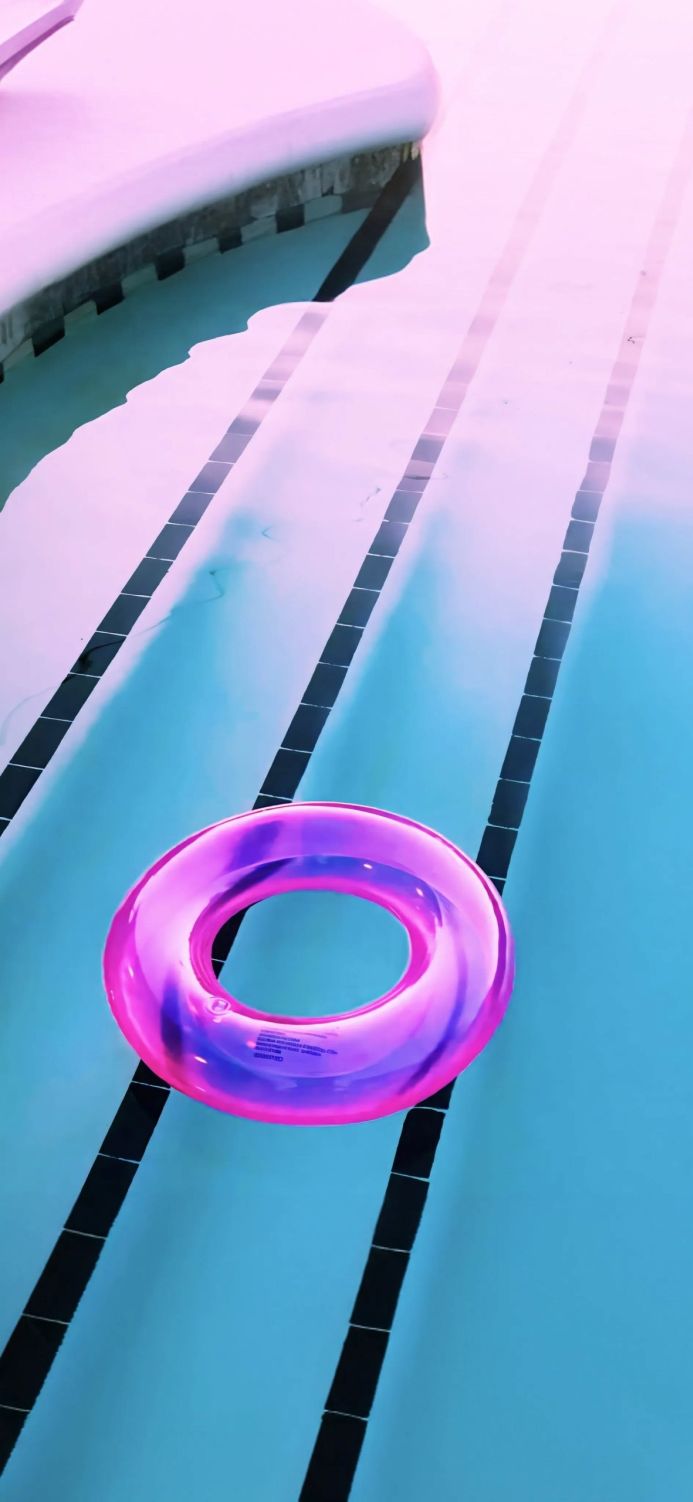 Pink inflatable ring floating in a swimming pool with black lane lines