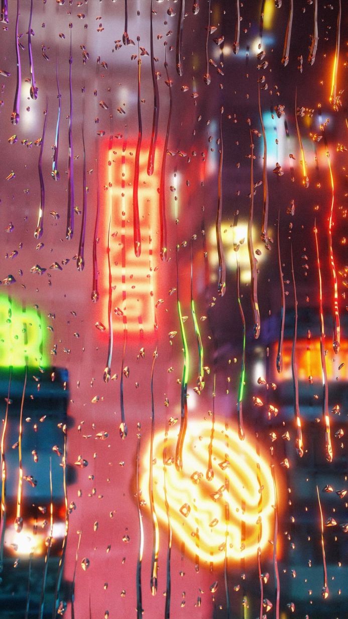 Raindrops on a window with blurred neon city lights in the background