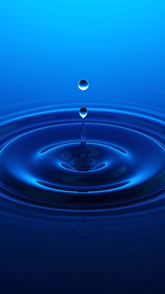 Water drop creating ripples in blue water
