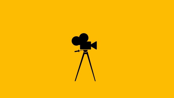 Black silhouette of vintage film camera on yellow