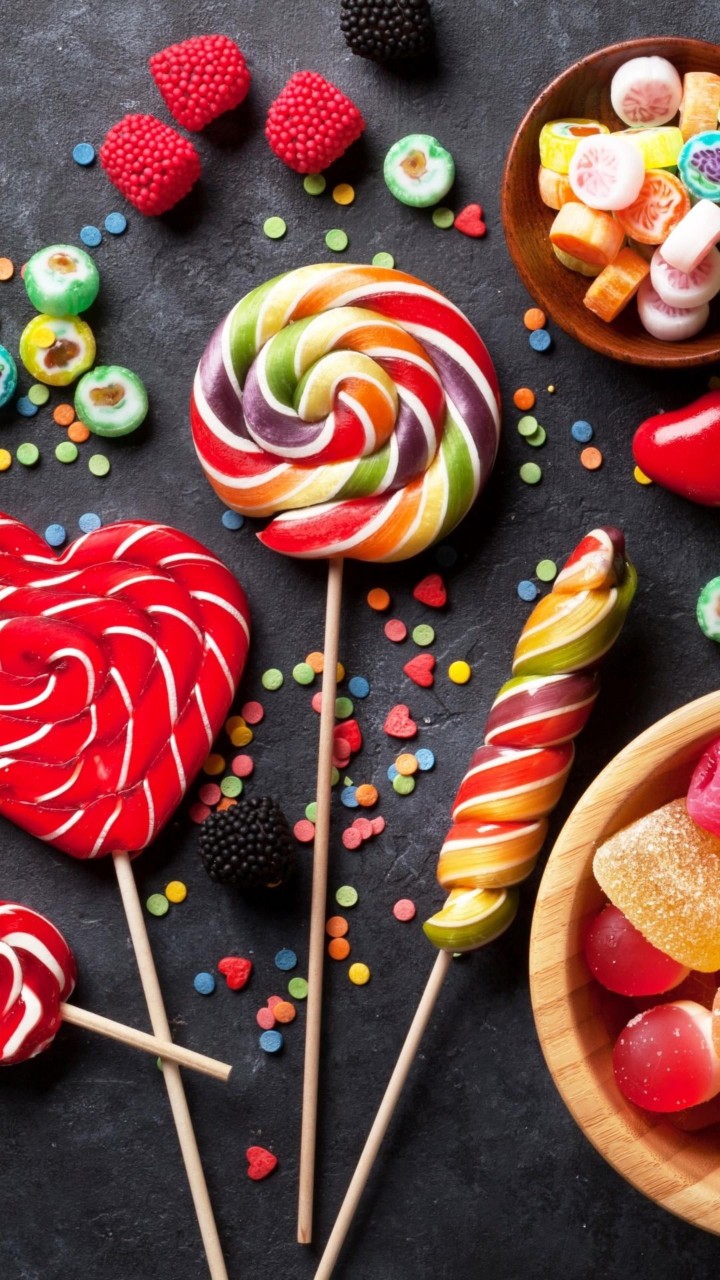 Colorful candies in bowls on a dark background